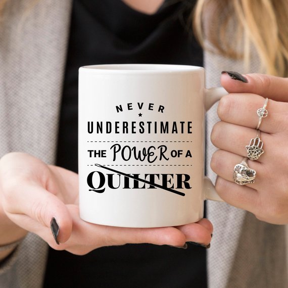 A humorous 11oz coffee mug featuring the quote 'Never Underestimate The Power Of A Quilter', crafted from high-quality ceramic.