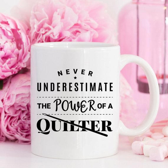 A humorous 11oz coffee mug featuring the quote 'Never Underestimate The Power Of A Quilter', crafted from high-quality ceramic.