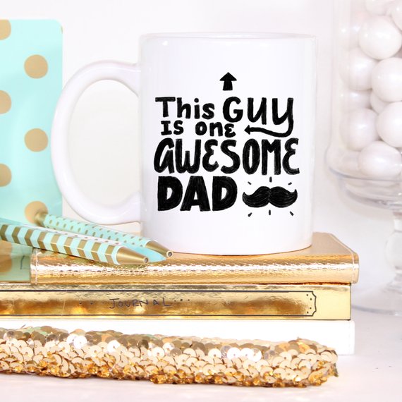 A humorous 11oz coffee mug with the text 'This Guy Is One Awesome Dad' printed on it, showcasing a fun design perfect for gifting.