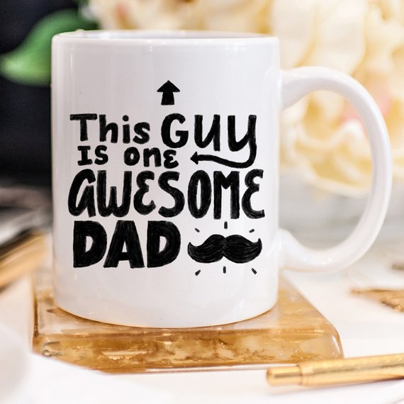 A humorous 11oz coffee mug with the text 'This Guy Is One Awesome Dad' printed on it, showcasing a fun design perfect for gifting.