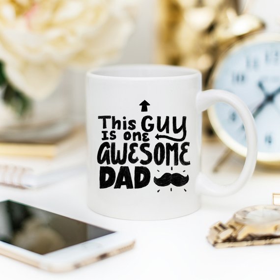 A humorous 11oz coffee mug with the text 'This Guy Is One Awesome Dad' printed on it, showcasing a fun design perfect for gifting.