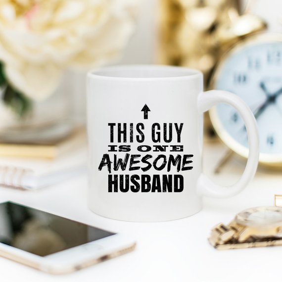 A humorous 11oz coffee mug with the text 'This Guy Is One Awesome Husband' printed on it, showcasing a fun design perfect for gifting.