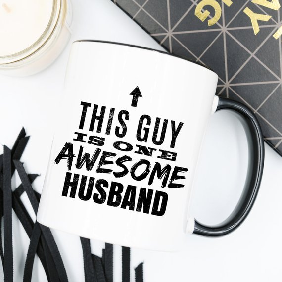 A humorous 11oz coffee mug with the text 'This Guy Is One Awesome Husband' printed on it, showcasing a fun design perfect for gifting.