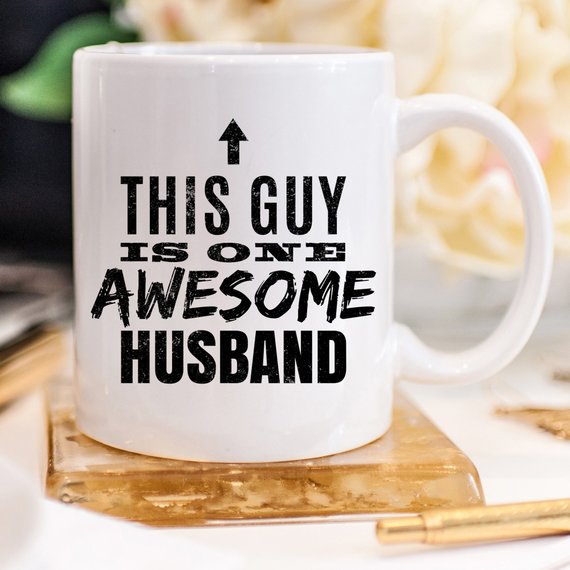 A humorous 11oz coffee mug with the text 'This Guy Is One Awesome Husband' printed on it, showcasing a fun design perfect for gifting.