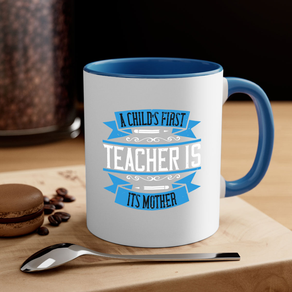 A stylish two-tone coffee mug with a colored handle and glossy finish, featuring the phrase 'A child’s first teacher is its mother'.