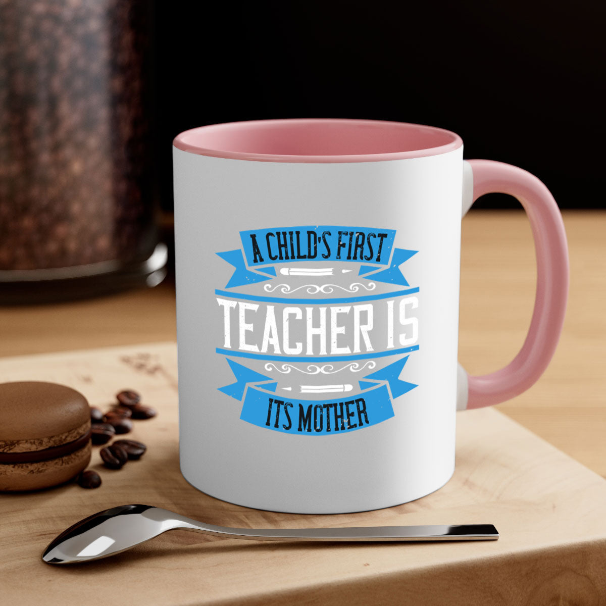 A stylish two-tone coffee mug with a colored handle and glossy finish, featuring the phrase 'A child’s first teacher is its mother'.