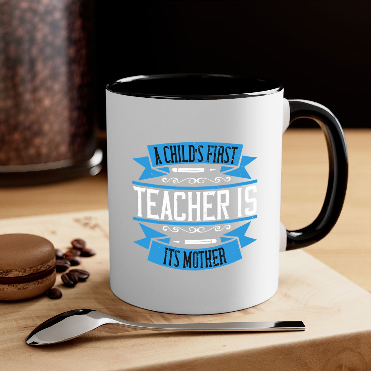 A stylish two-tone coffee mug with a colored handle and glossy finish, featuring the phrase 'A child’s first teacher is its mother'.