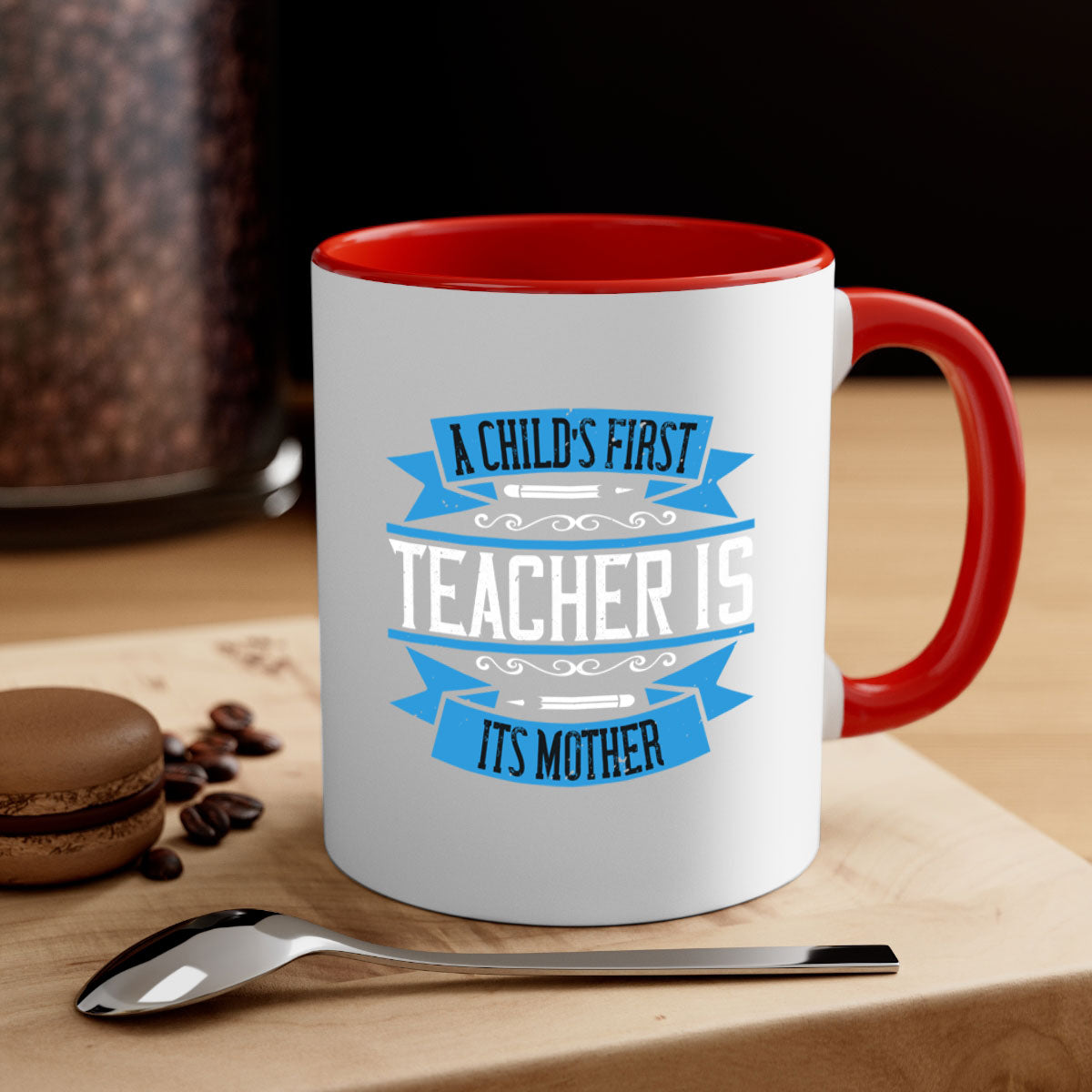 A stylish two-tone coffee mug with a colored handle and glossy finish, featuring the phrase 'A child’s first teacher is its mother'.