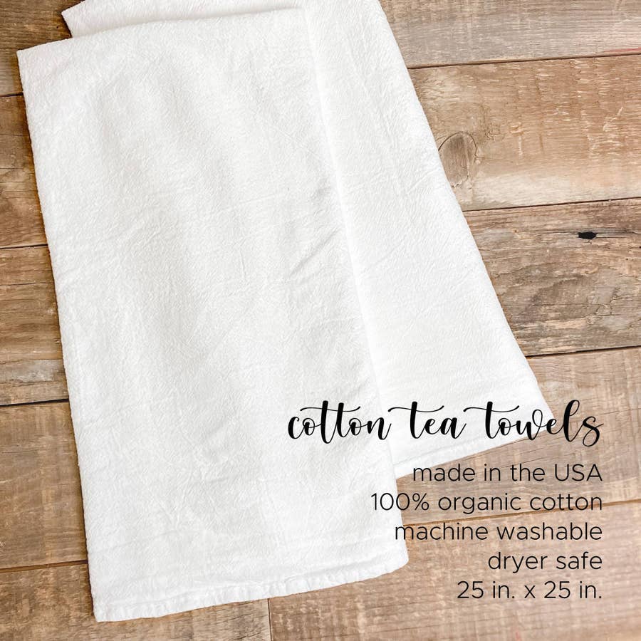 Adventure Awaits cotton tea towel featuring a vibrant mountain design, made from 100% absorbent cotton with hemmed edges.