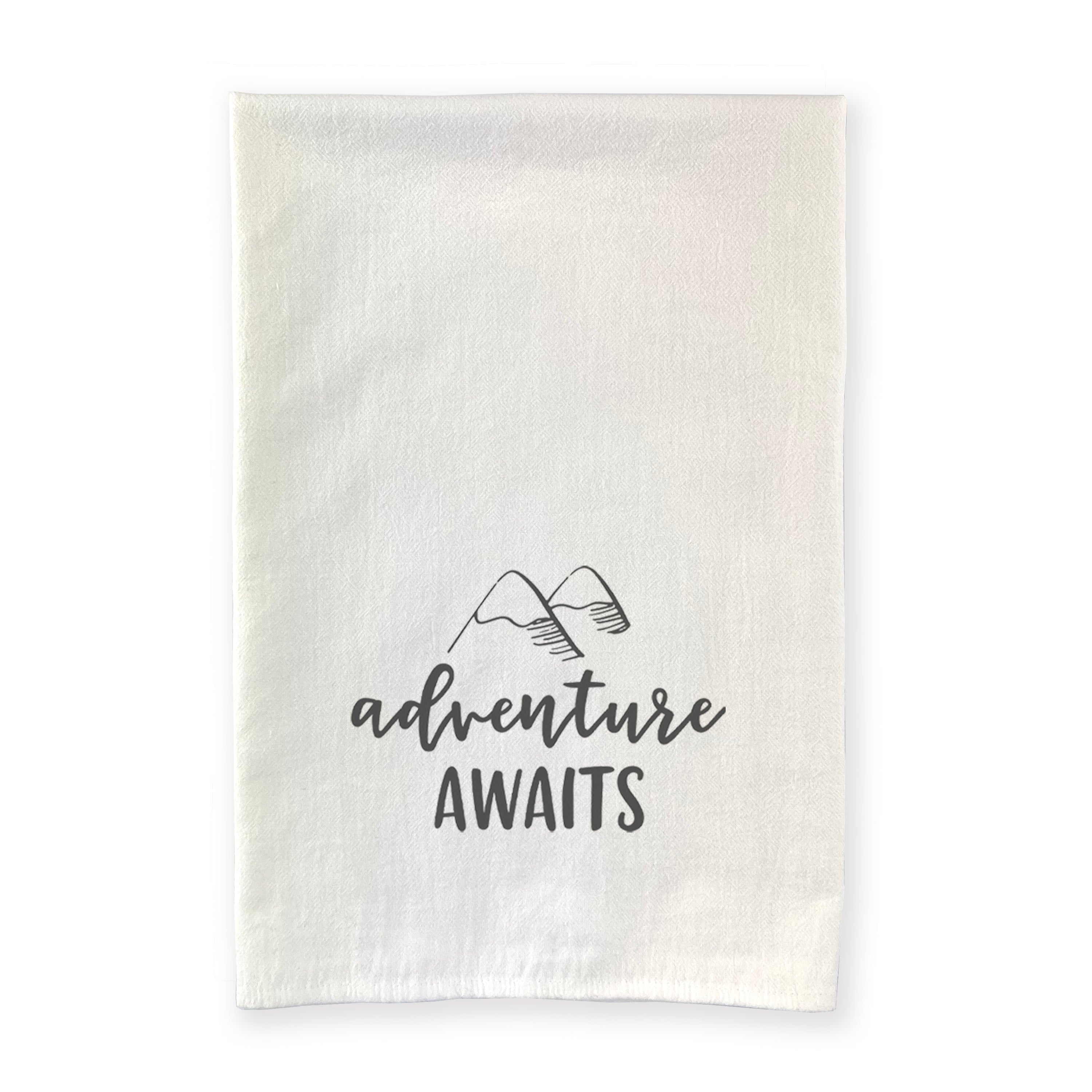 Adventure Awaits cotton tea towel featuring a vibrant mountain design, made from 100% absorbent cotton with hemmed edges.