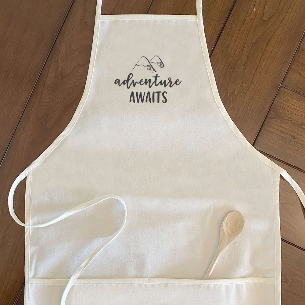 Adventure Awaits Women's Apron featuring a mountain design, made of cotton canvas with adjustable neck and twill ties.