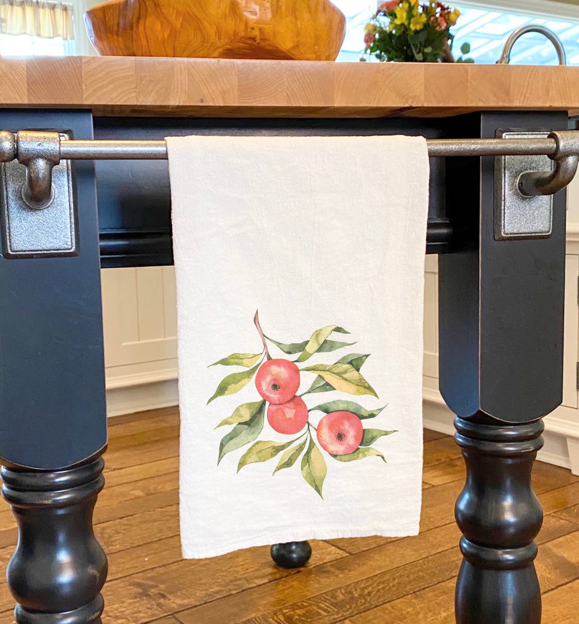 A beautifully designed cotton tea towel featuring vibrant apples on a branch, perfect for kitchen use and decor.