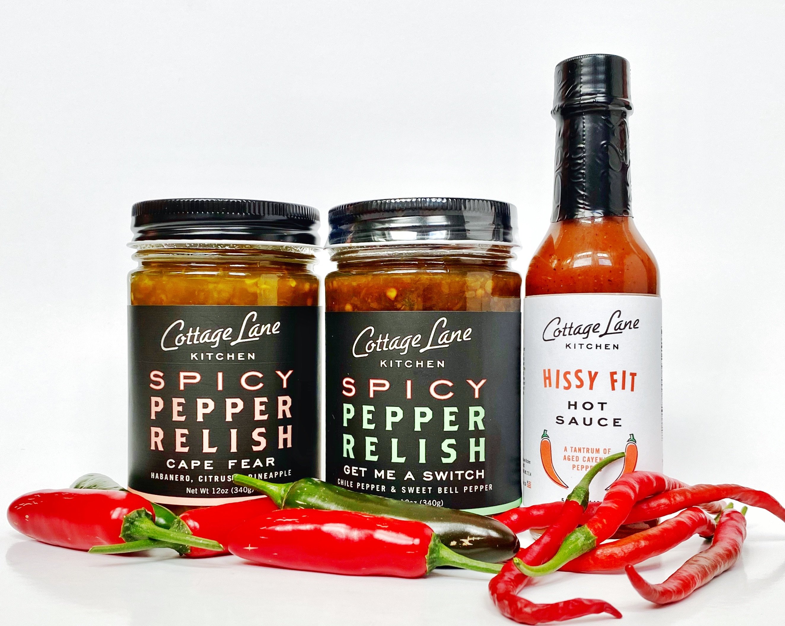 A collection of three bottles featuring award-winning spicy pepper relishes and hot sauce, showcasing vibrant labels and enticing colors.