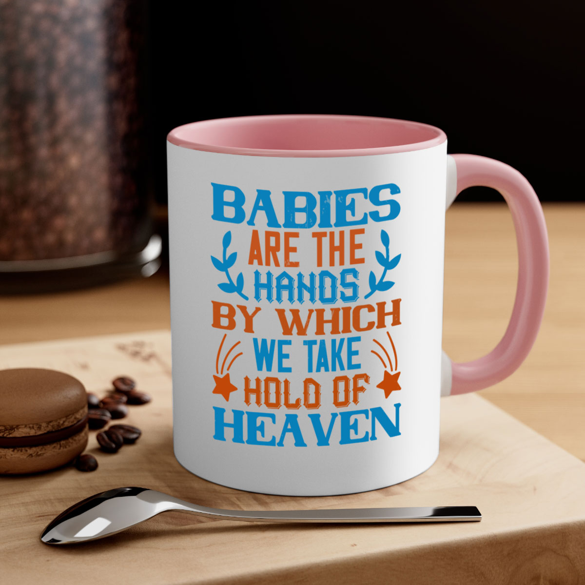 A stylish two-tone ceramic mug with a colored handle and interior, featuring the phrase 'Babies are the hands by which we take hold of heaven'.