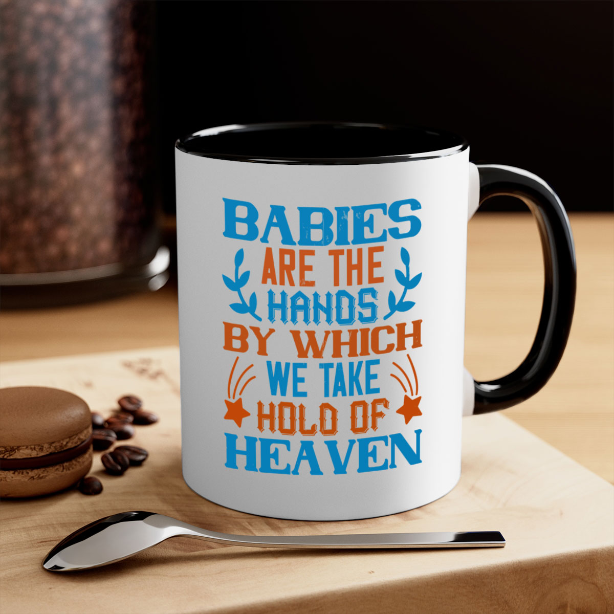 A stylish two-tone ceramic mug with a colored handle and interior, featuring the phrase 'Babies are the hands by which we take hold of heaven'.