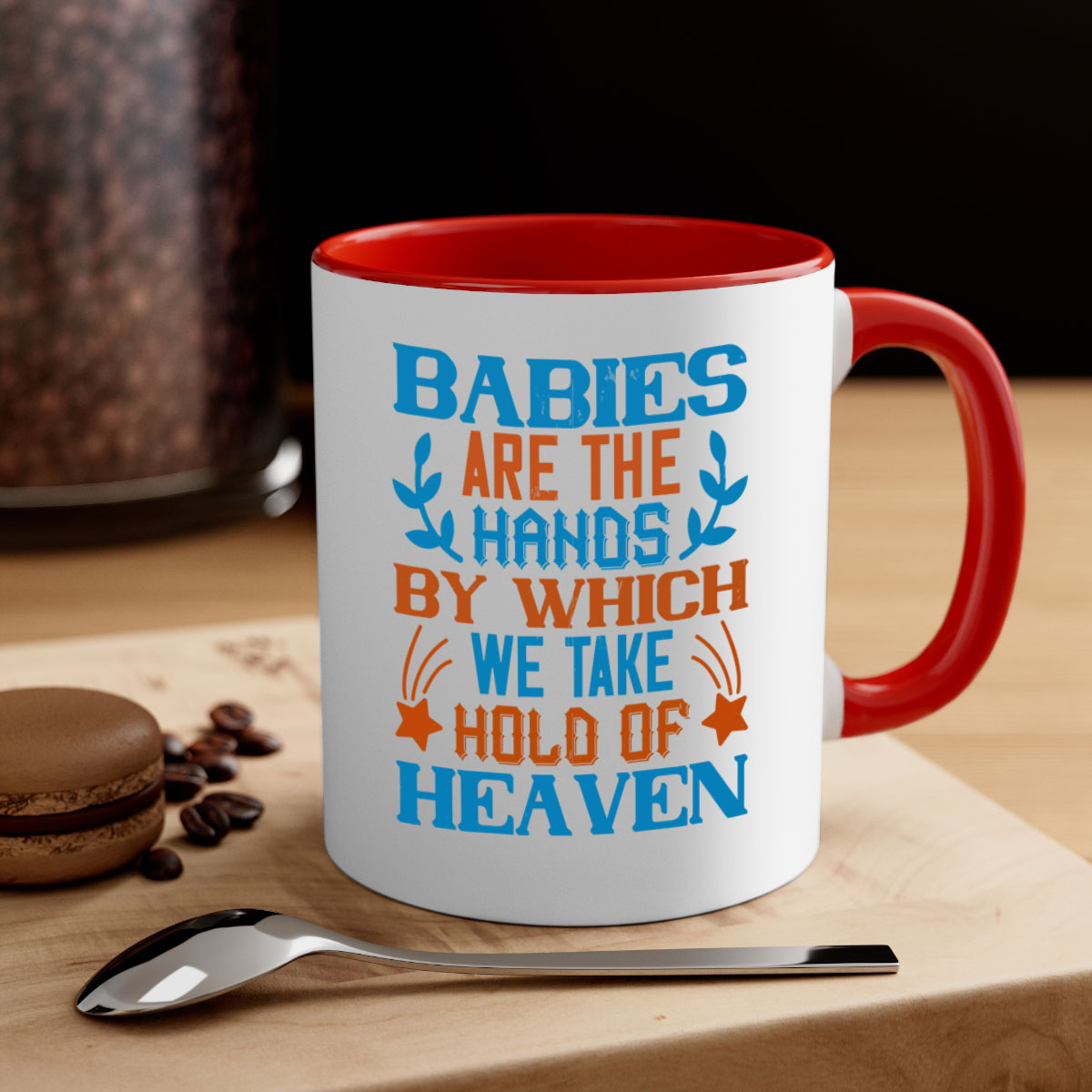 A stylish two-tone ceramic mug with a colored handle and interior, featuring the phrase 'Babies are the hands by which we take hold of heaven'.