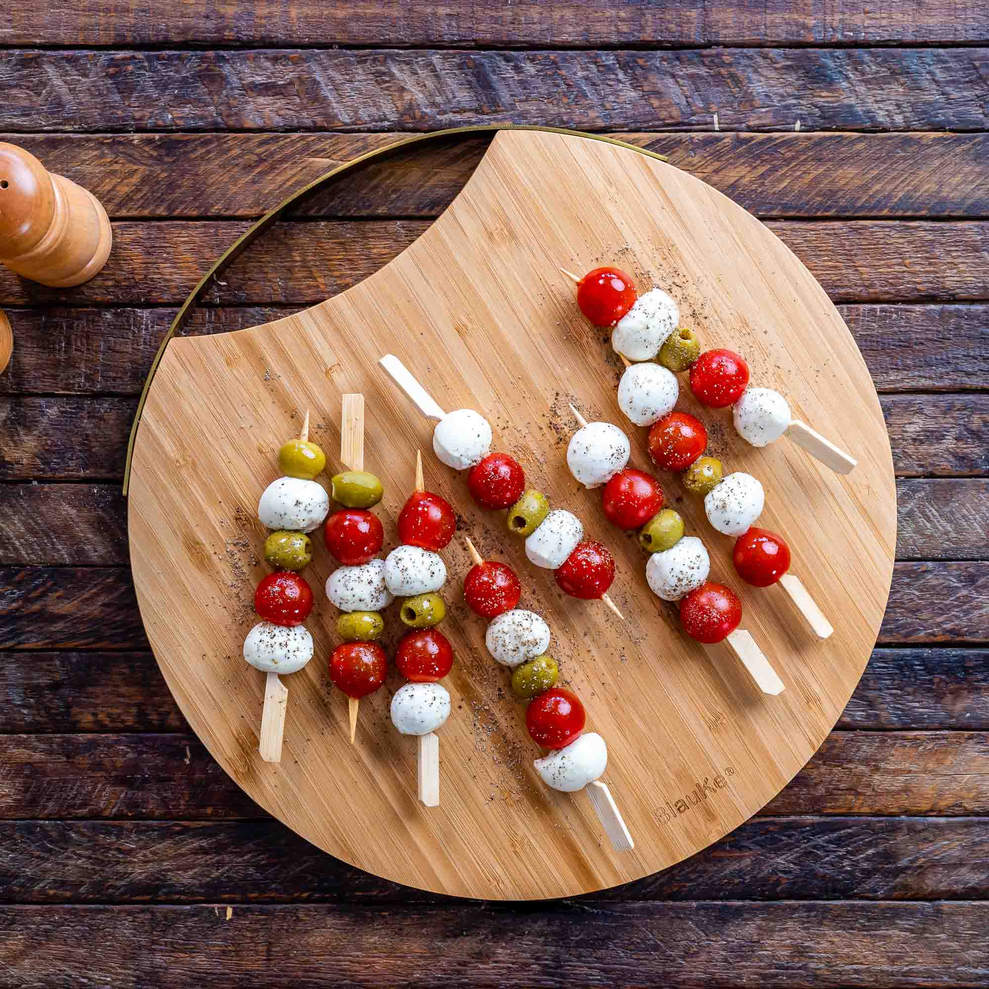 A stylish 13-inch bamboo cheese board with magnetic knife storage, featuring a spatula knife, plane knife, and serving fork, elegantly arranged for serving.