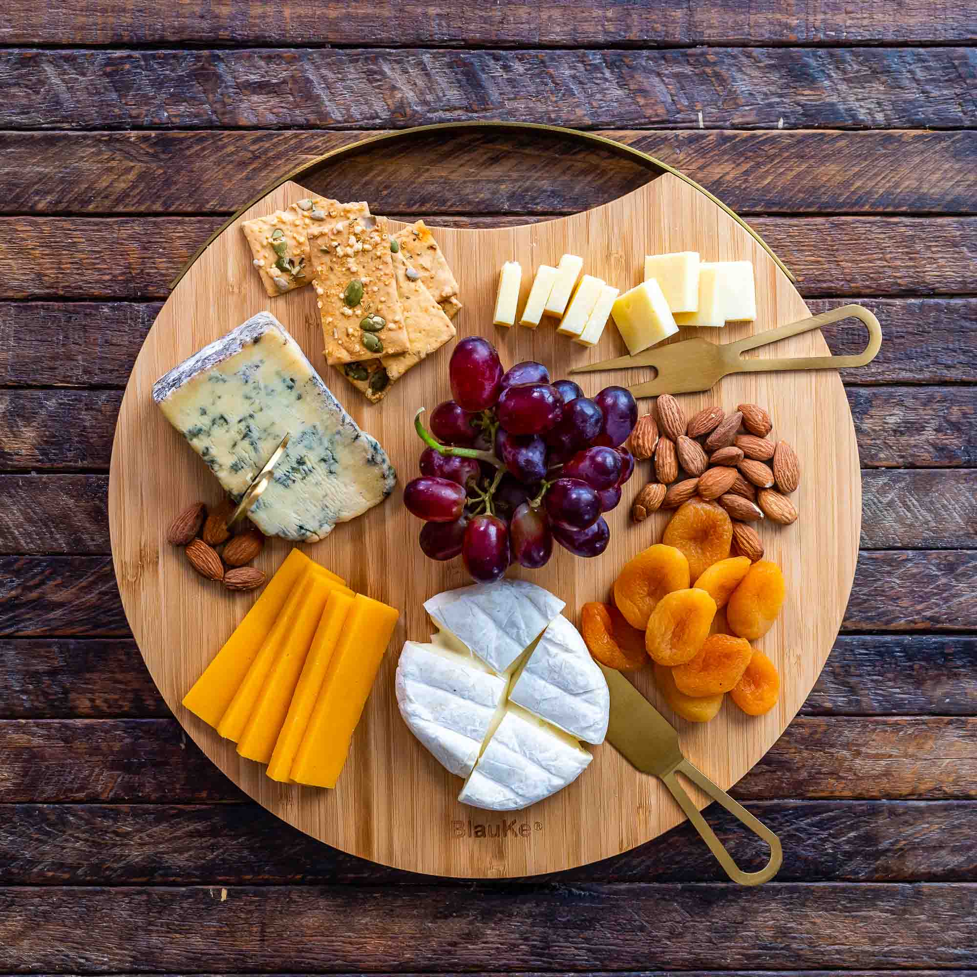 A stylish 13-inch bamboo cheese board with magnetic knife storage, featuring a spatula knife, plane knife, and serving fork, elegantly arranged for serving.