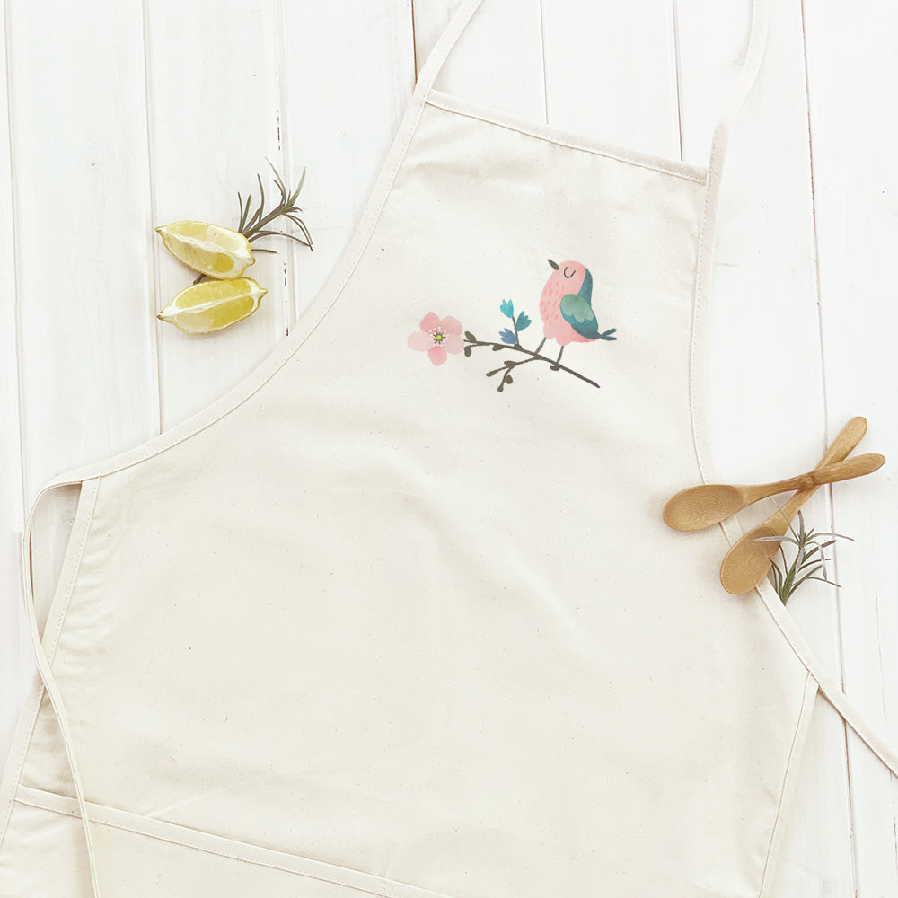 A stylish women's apron featuring a beautiful cherry blossom design with a bird, made from durable cotton canvas.