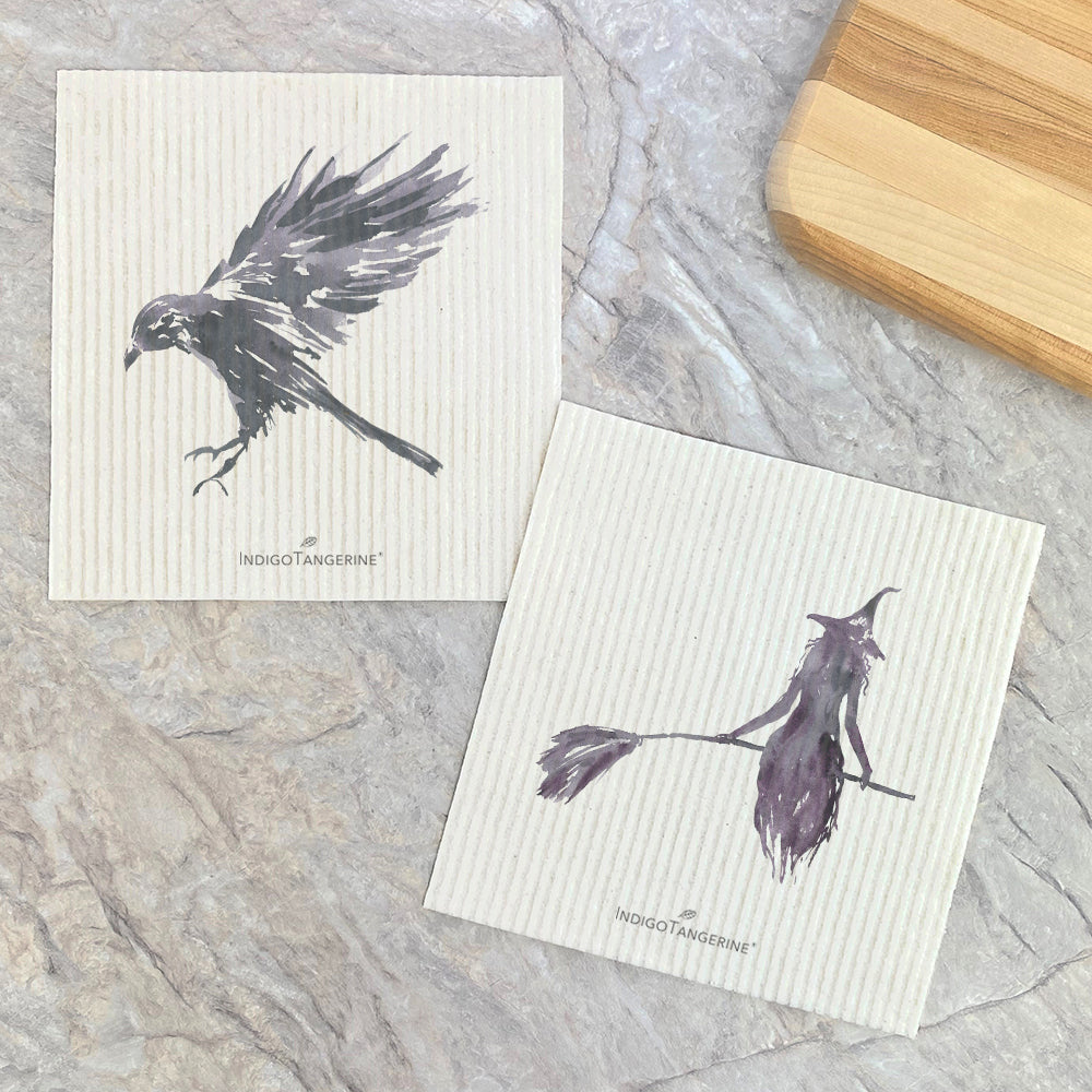 Two eco-friendly Swedish dishcloths featuring a black raven and witch silhouette design, perfect for sustainable cleaning.