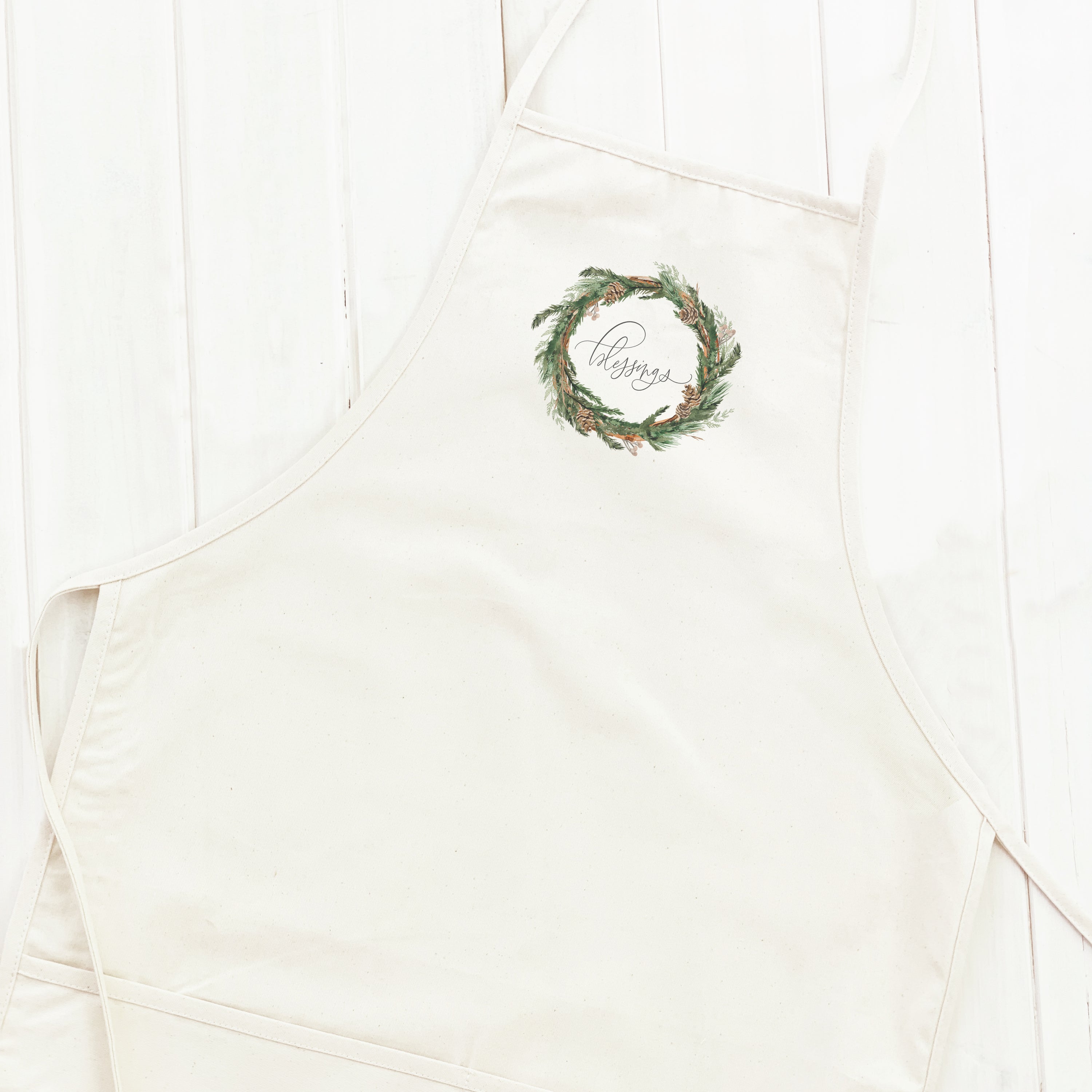 Blessings Wreath Women's Apron featuring a beautiful wreath design, adjustable neck strap, and divided front pocket, made from durable cotton canvas.