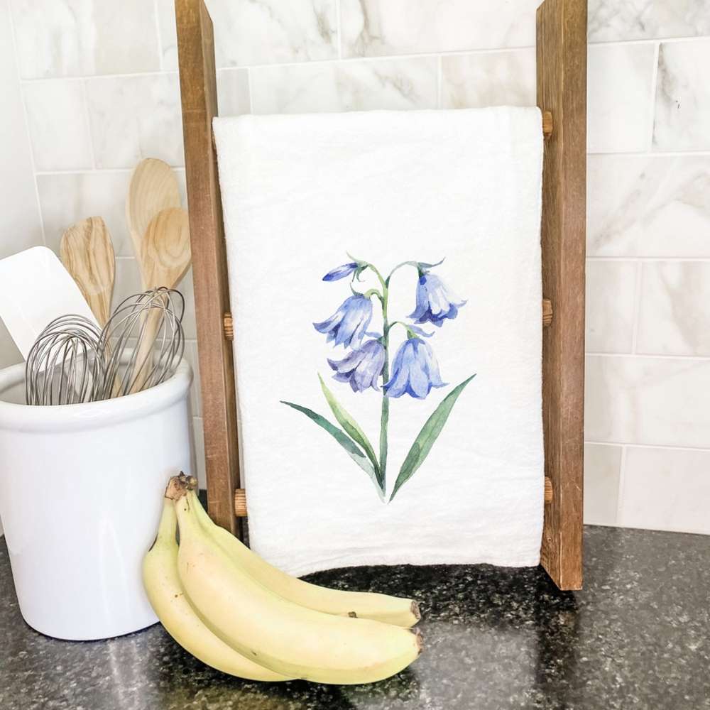 A vibrant Bluebells Cotton Tea Towel featuring a floral design, made from 100% absorbent cotton, displayed on a kitchen countertop.