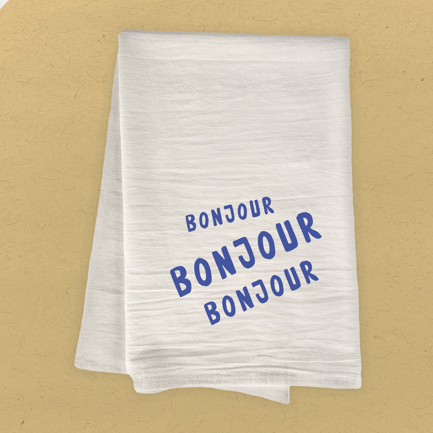 Bonjour Trois Cotton Tea Towel featuring vibrant design, 100% absorbent cotton, and hemmed edges, measuring 27 inches square.