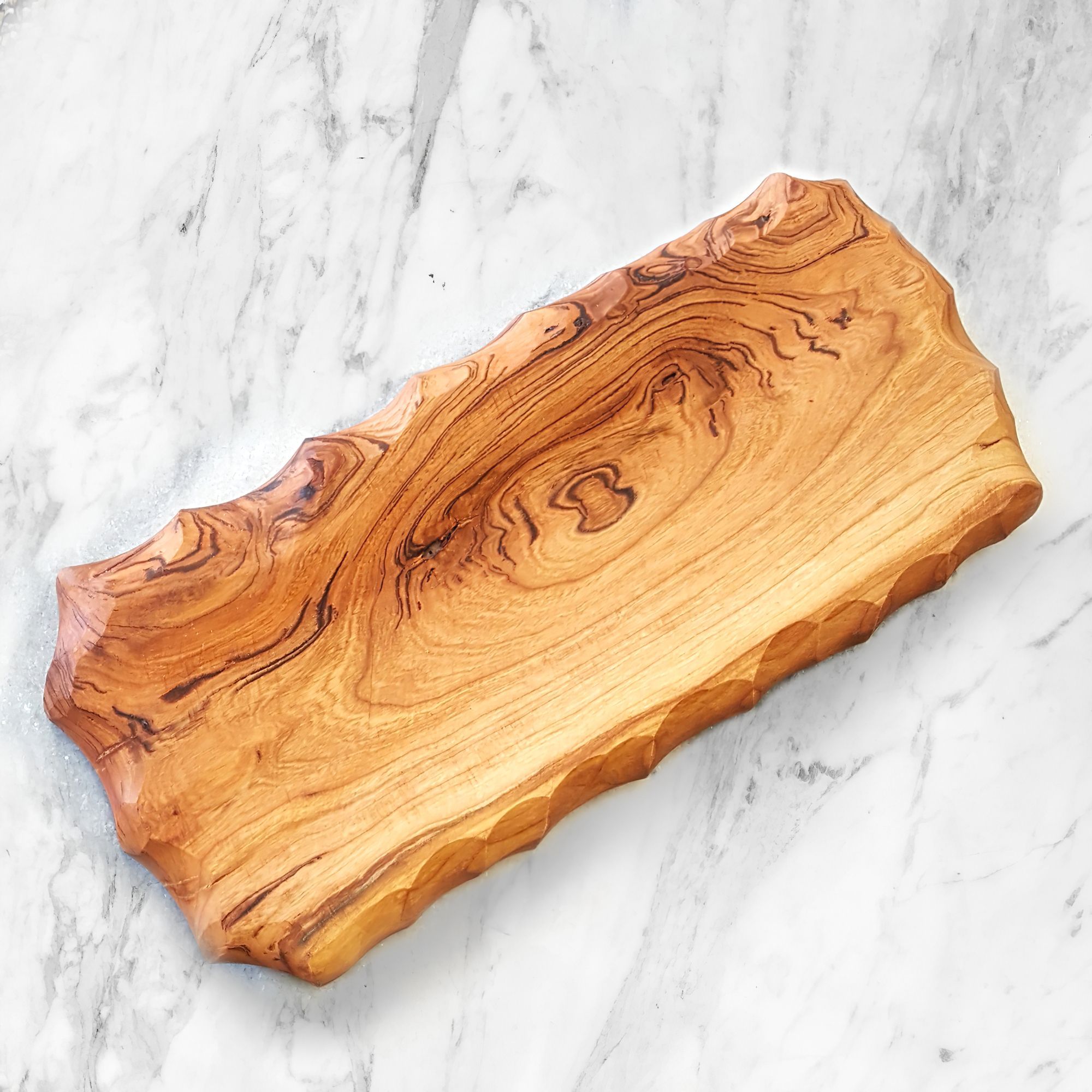 Handcarved wooden bread board with chiseled edging, perfect for serving loaves and steaks.