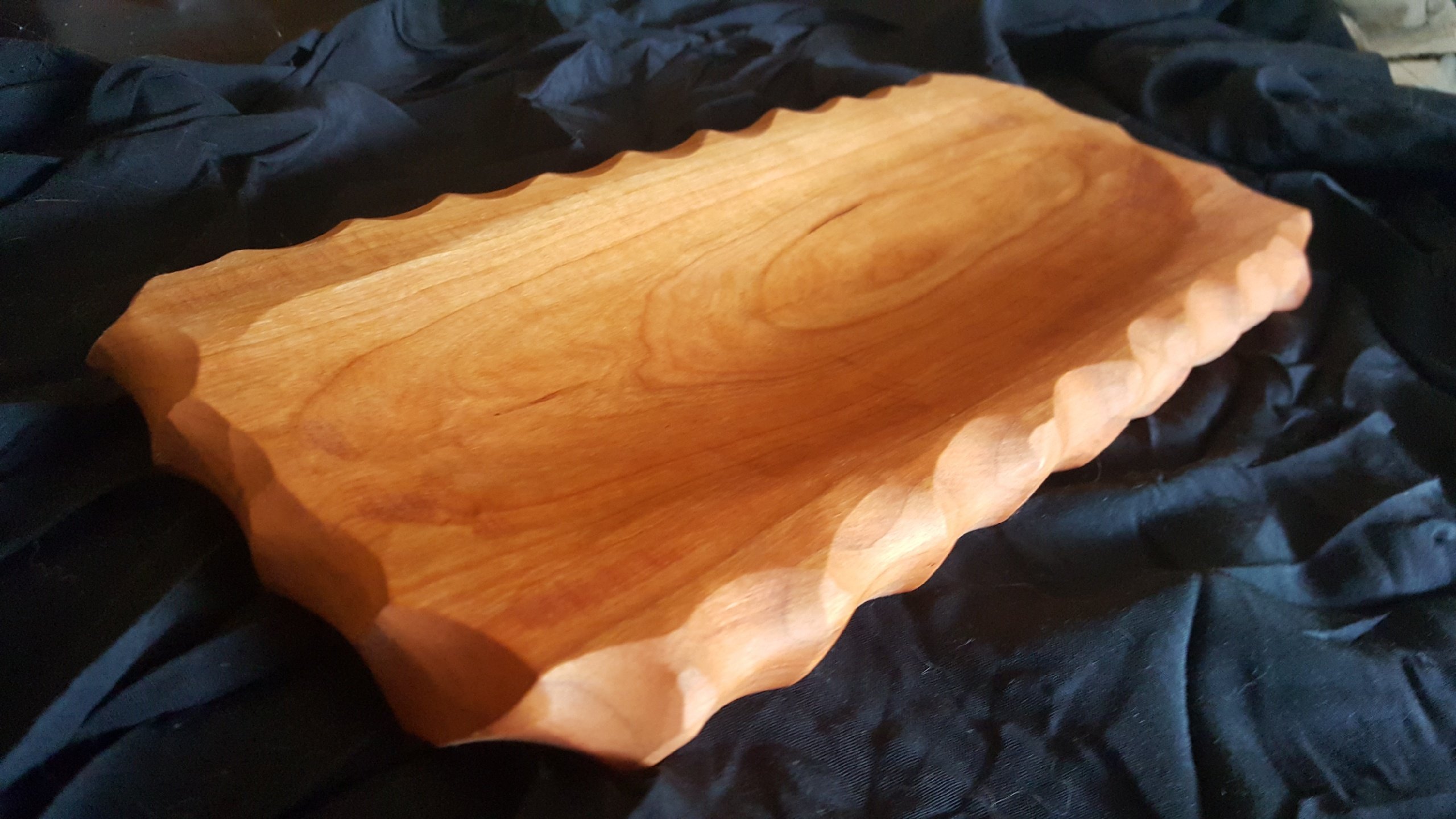 Handcarved wooden bread board with chiseled edging, perfect for serving loaves and steaks.