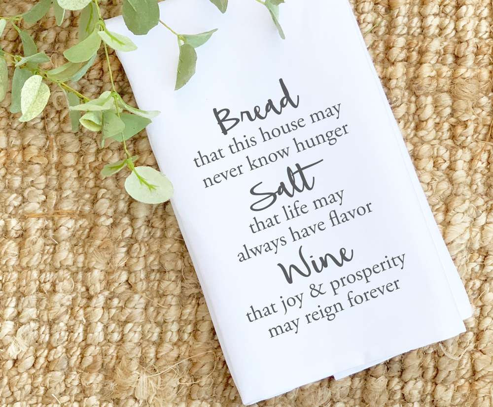 A beautifully designed cotton tea towel featuring the words 'Bread, Salt, Wine', made from absorbent material with vibrant colors.