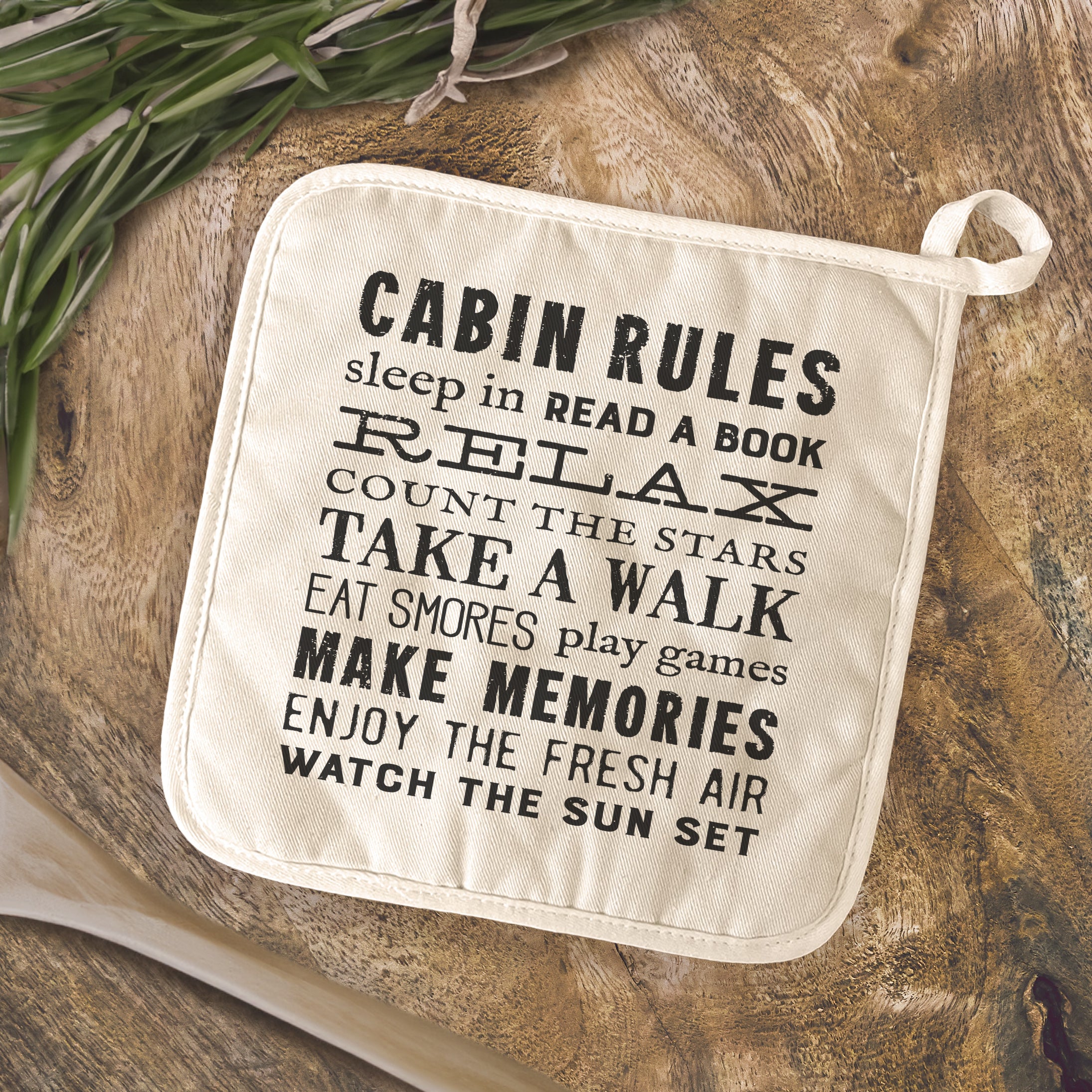 Cabin Rules Cotton Pot Holder featuring vibrant designs and a convenient hanging loop, perfect for protecting surfaces from hot cookware.