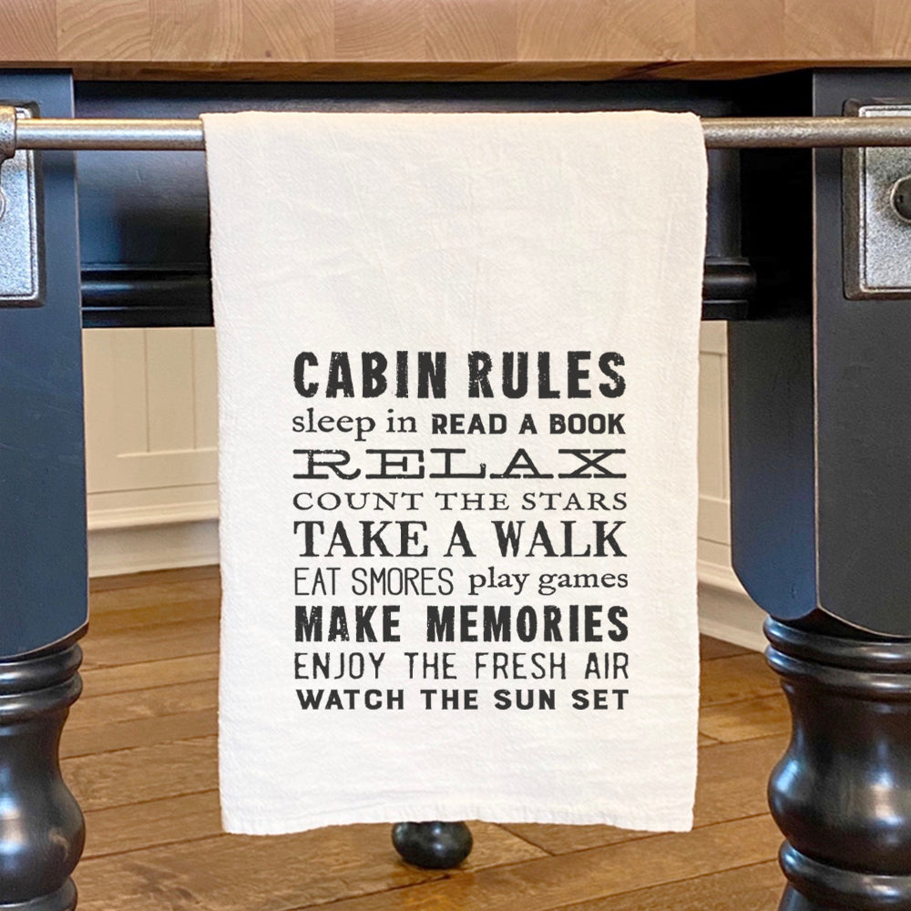 A vibrant Cabin Rules Cotton Tea Towel featuring a rustic design, made from 100% absorbent cotton, perfect for kitchen use.