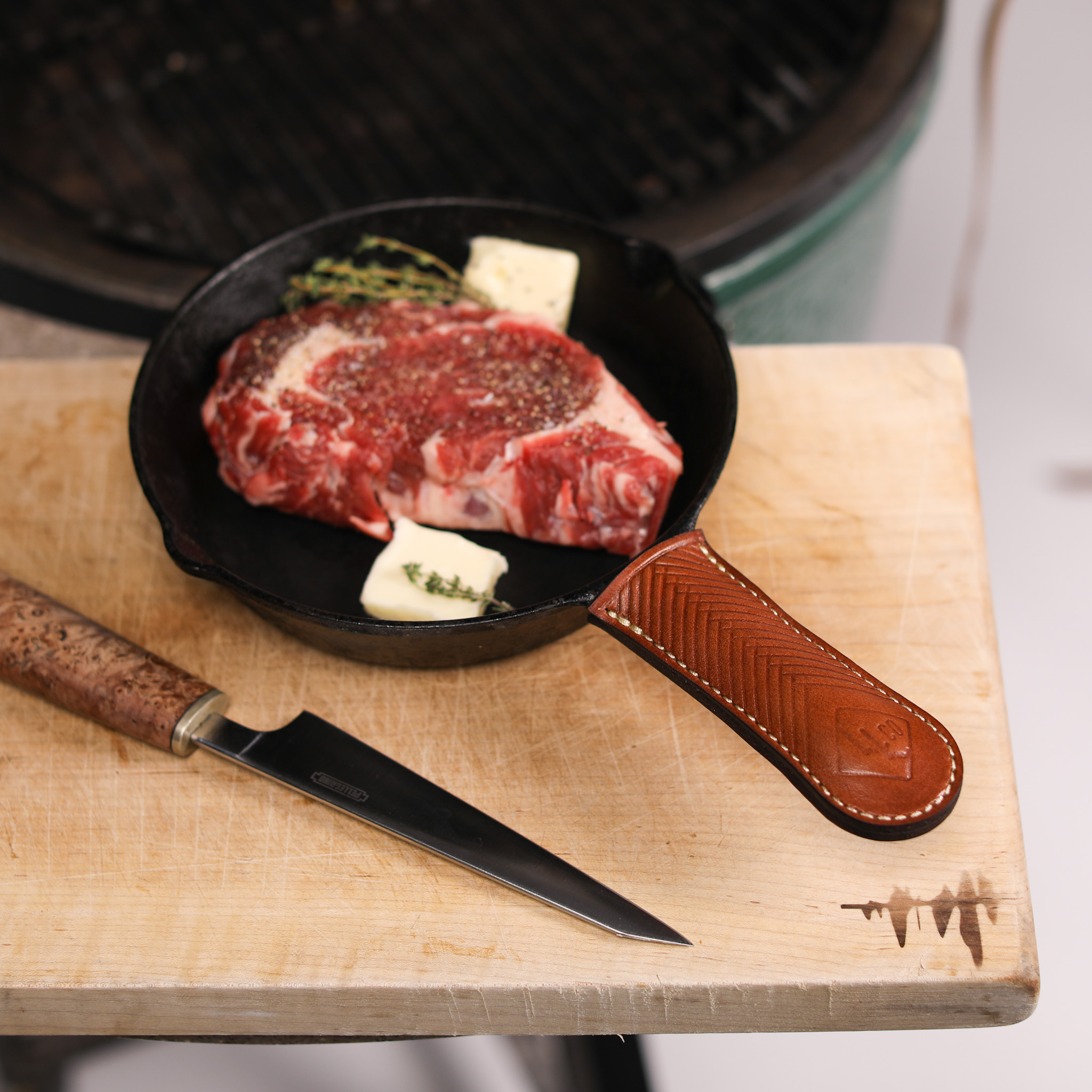 A pair of handcrafted leather cast-iron handle covers, showcasing their elegant design and durable material, perfect for protecting hands while cooking.