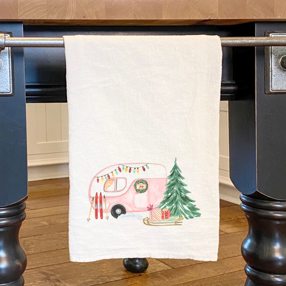 A vibrant cotton tea towel featuring a Christmas camper design, perfect for holiday kitchen use.