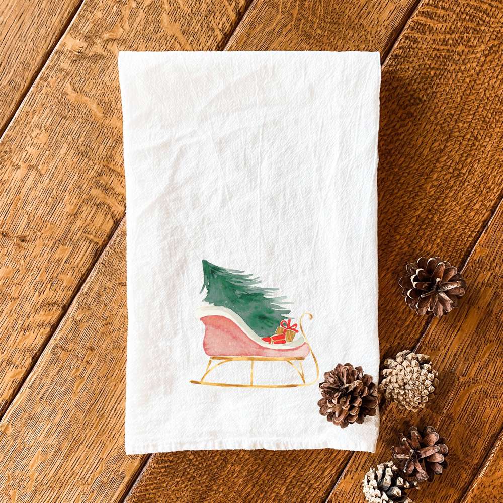 A vibrant cotton tea towel featuring a Christmas sleigh design, perfect for holiday kitchen decor.