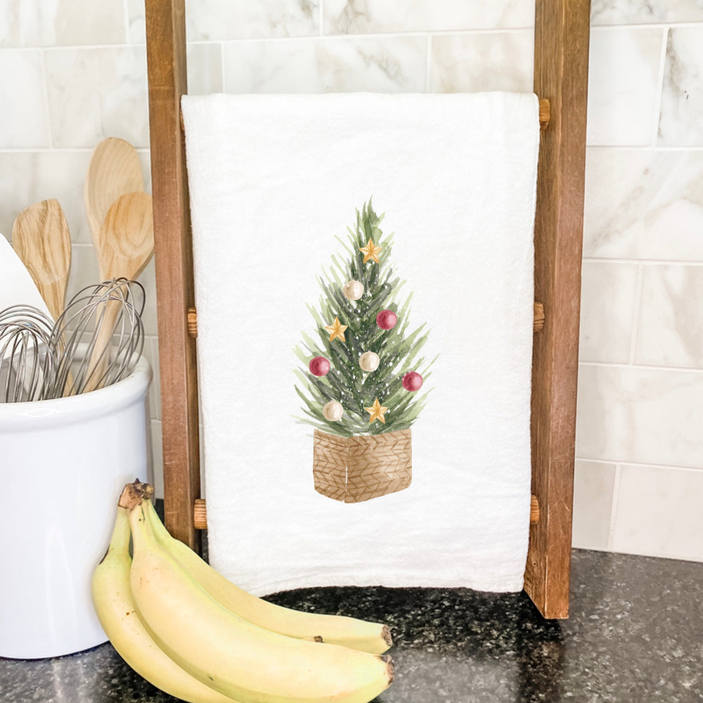 A beautifully designed cotton tea towel featuring a Christmas tree basket, showcasing vibrant colors and hemmed edges, perfect for holiday kitchens.