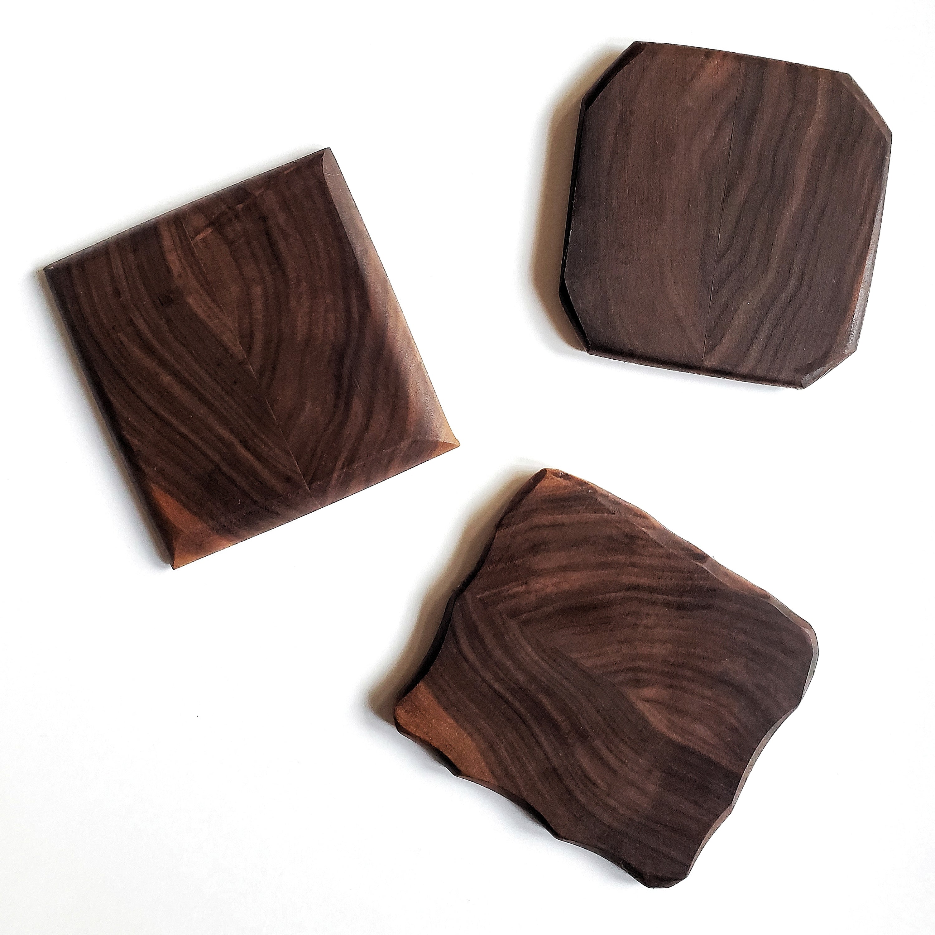 Set of four 4x4 beveled edge wooden coasters in black walnut, cherry, and maple finishes.