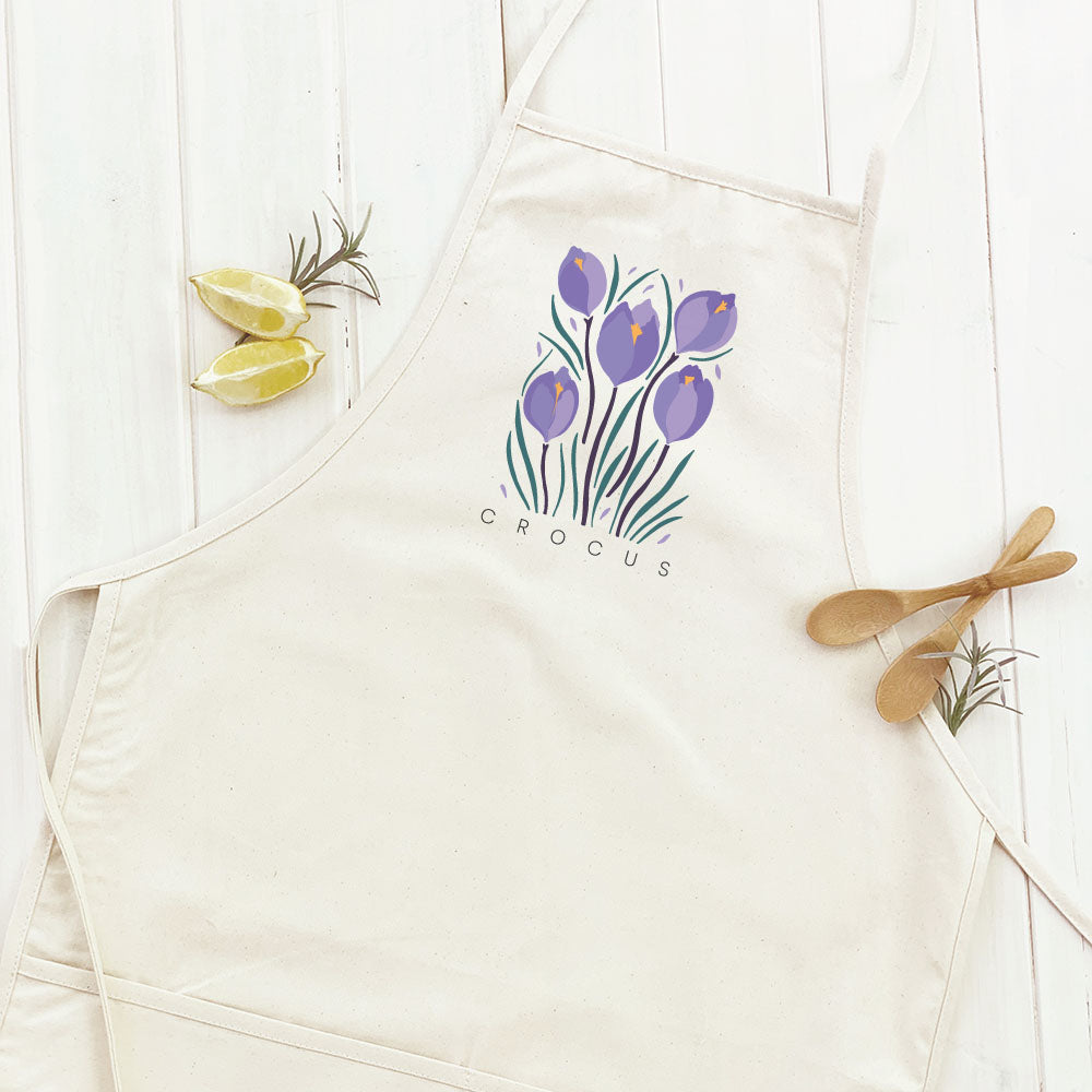 Crocus Women's Apron in garden setting, featuring elegant design and divided front pocket.