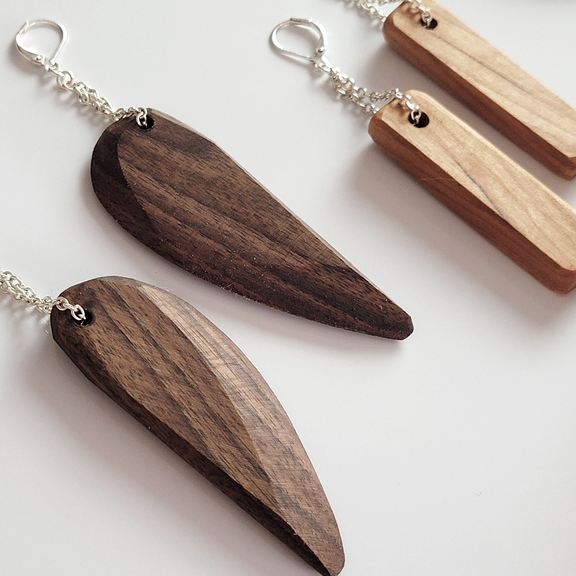 Handmade wooden dangle earrings in feather shape, featuring cherry and walnut finishes with silver plated attachments.