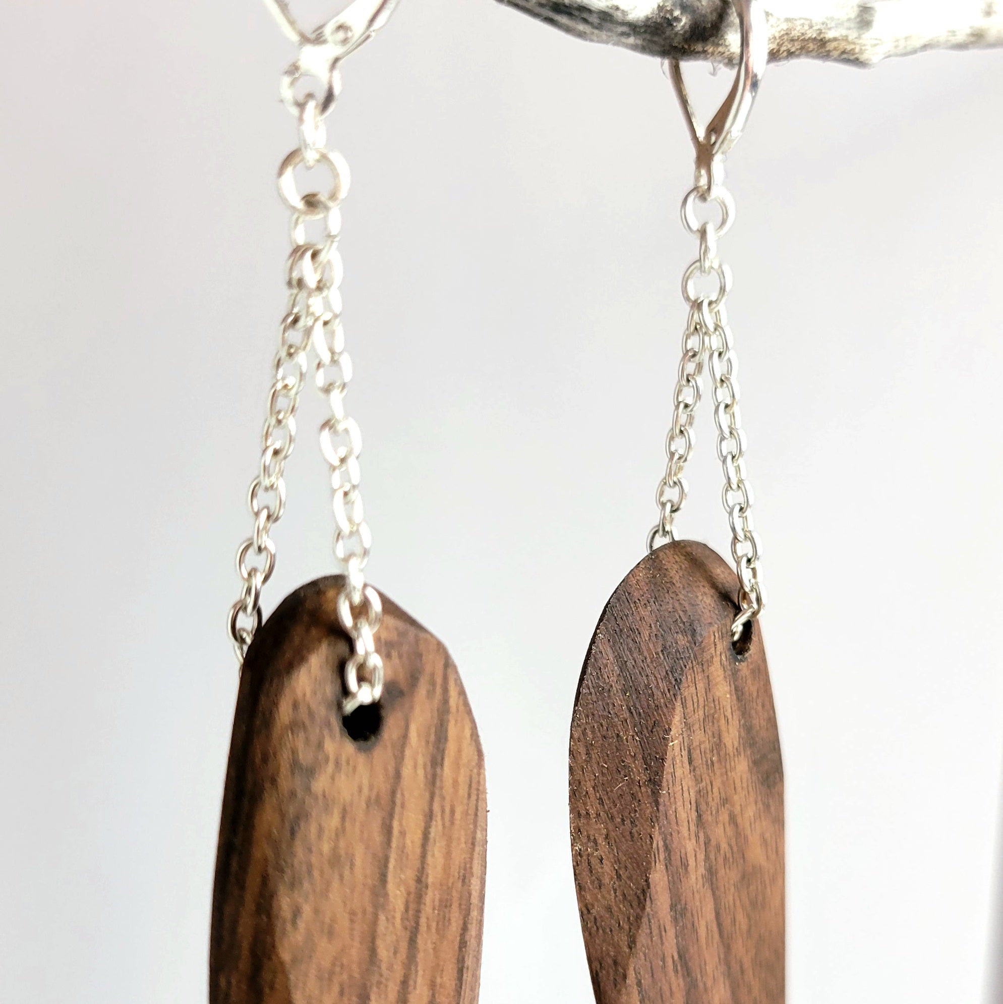 Handmade wooden dangle earrings in feather shape, featuring cherry and walnut finishes with silver plated attachments.