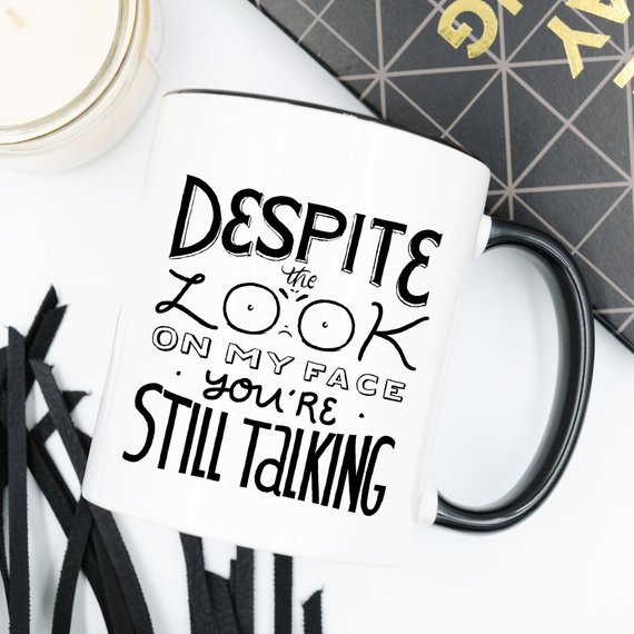 A humorous coffee mug featuring the phrase 'Despite The Look On My Face, You're Still Talking', crafted from high-quality ceramic with a glossy finish.