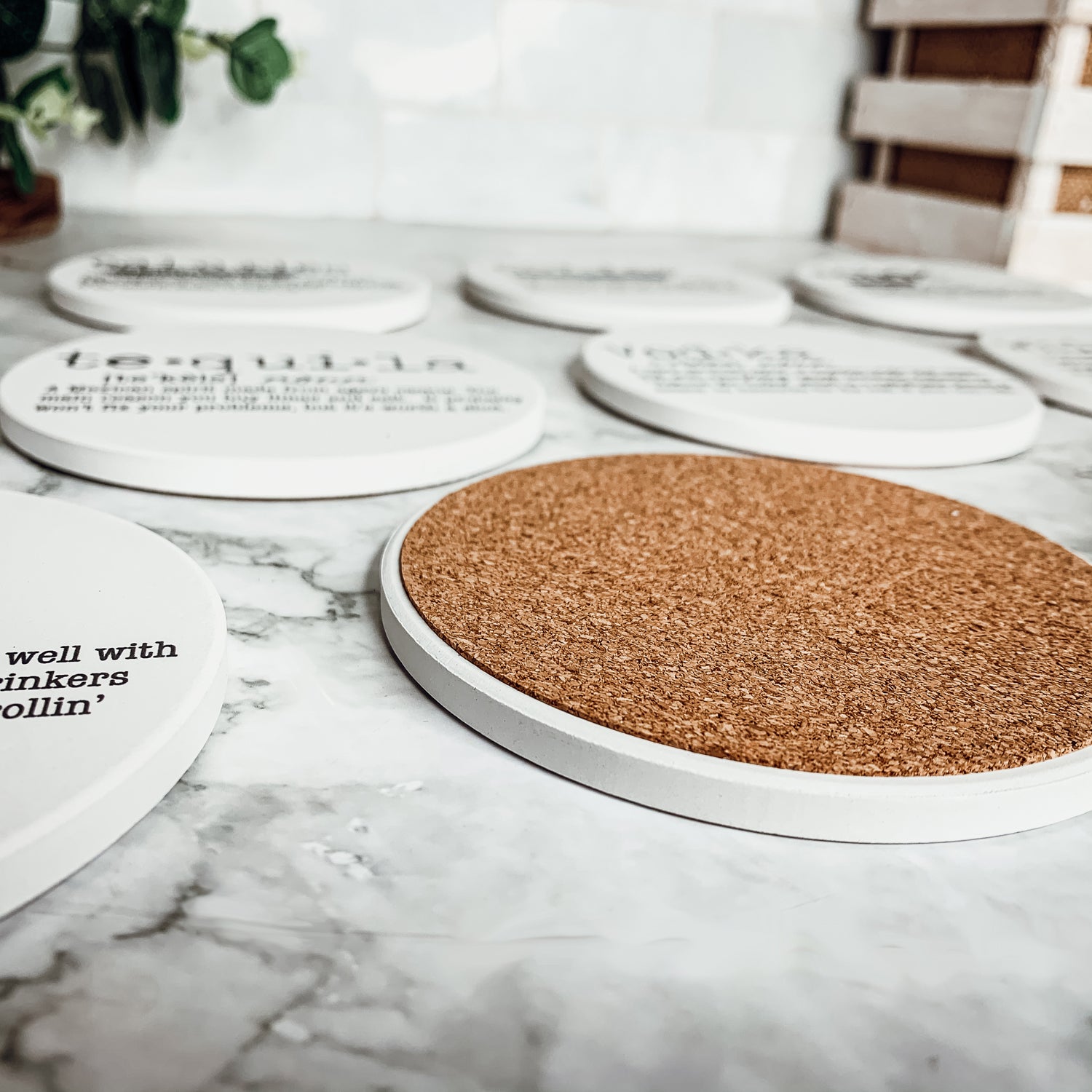 A set of ceramic coasters featuring funny dictionary quotes, showcasing their unique design and cork backing.