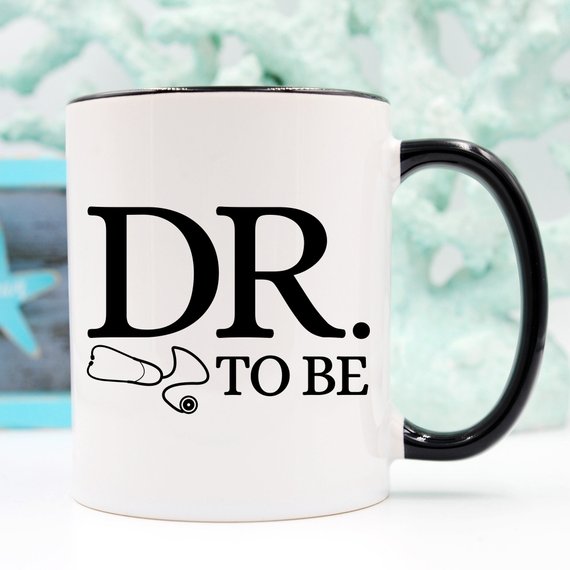 A humorous Dr. To Be coffee mug featuring a witty design, perfect for medical students and coffee lovers, made from high-quality ceramic.