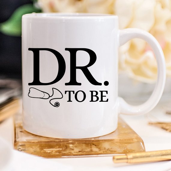 A humorous Dr. To Be coffee mug featuring a witty design, perfect for medical students and coffee lovers, made from high-quality ceramic.