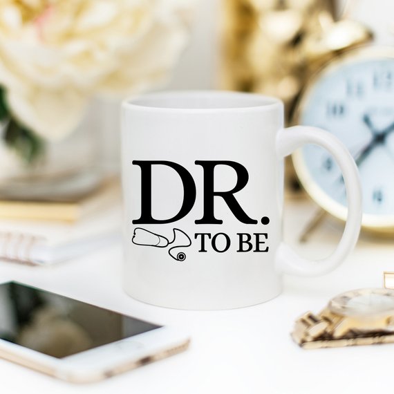 A humorous Dr. To Be coffee mug featuring a witty design, perfect for medical students and coffee lovers, made from high-quality ceramic.