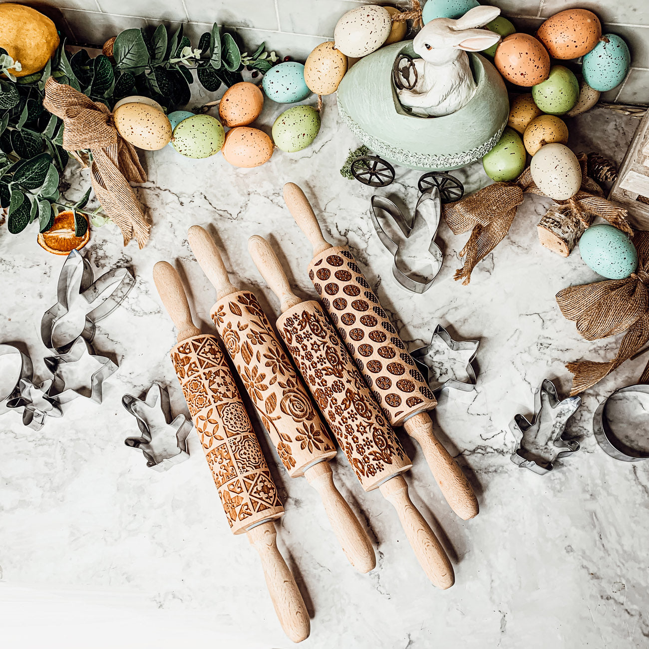 Colorful Easter and Spring rolling pins with floral and bunny designs, accompanied by two metal cookie cutters, perfect for festive baking.