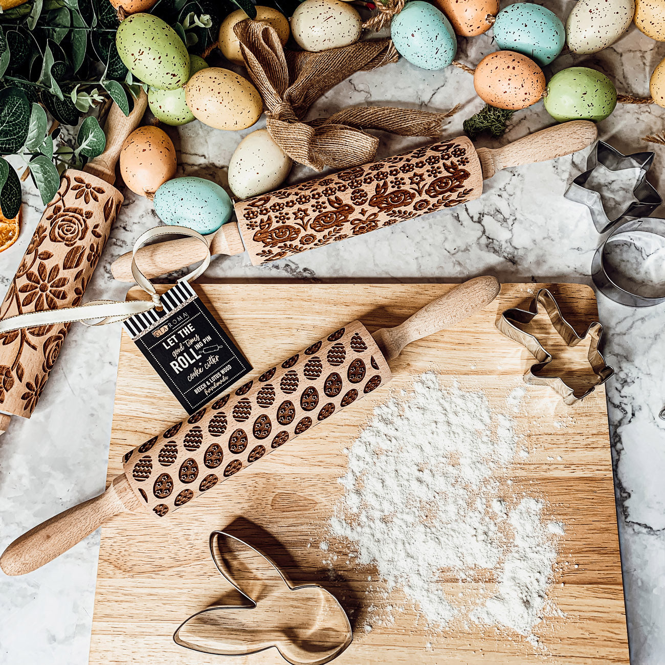 Colorful Easter and Spring rolling pins with floral and bunny designs, accompanied by two metal cookie cutters, perfect for festive baking.