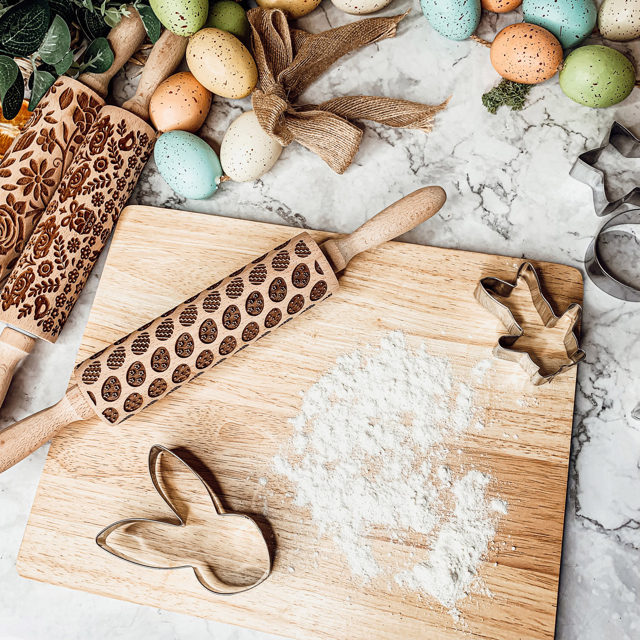 Colorful Easter and Spring rolling pins with floral and bunny designs, accompanied by two metal cookie cutters, perfect for festive baking.