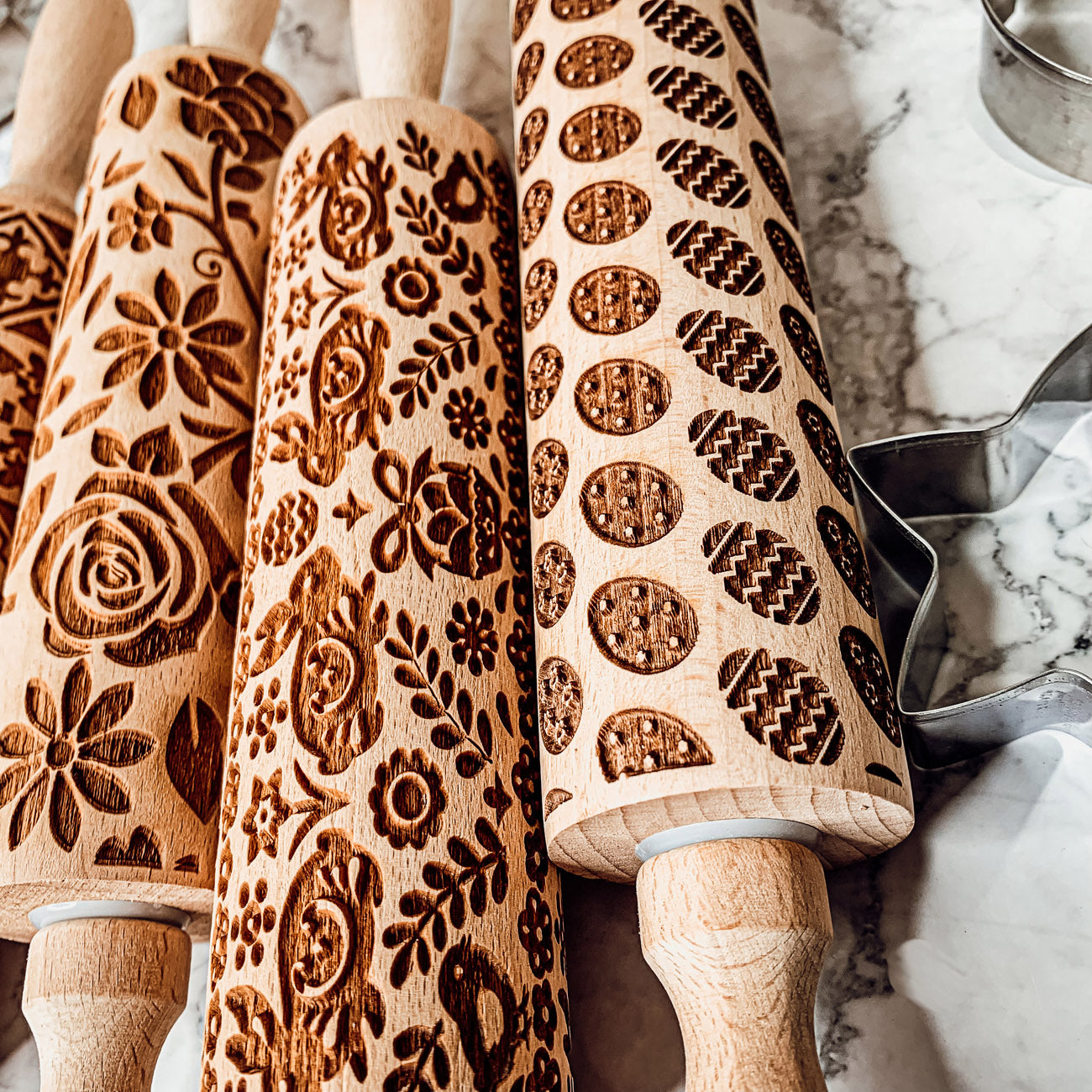 Colorful Easter and Spring rolling pins with floral and bunny designs, accompanied by two metal cookie cutters, perfect for festive baking.