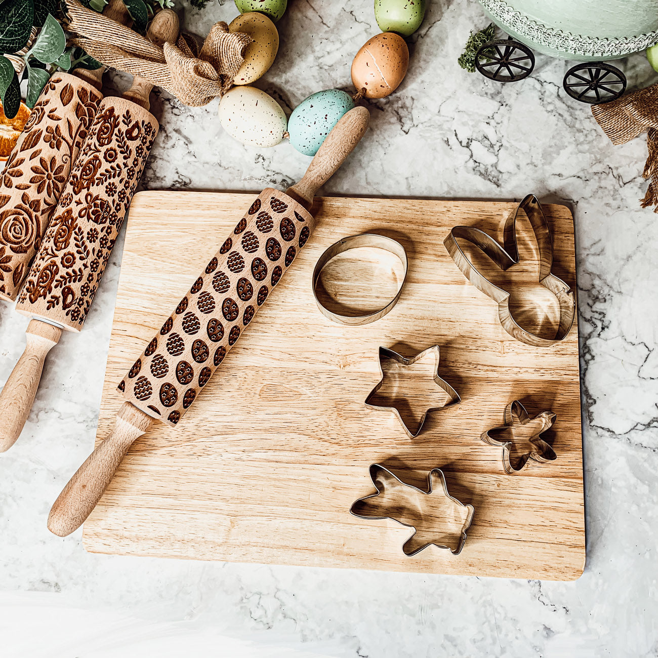 Colorful Easter and Spring rolling pins with floral and bunny designs, accompanied by two metal cookie cutters, perfect for festive baking.